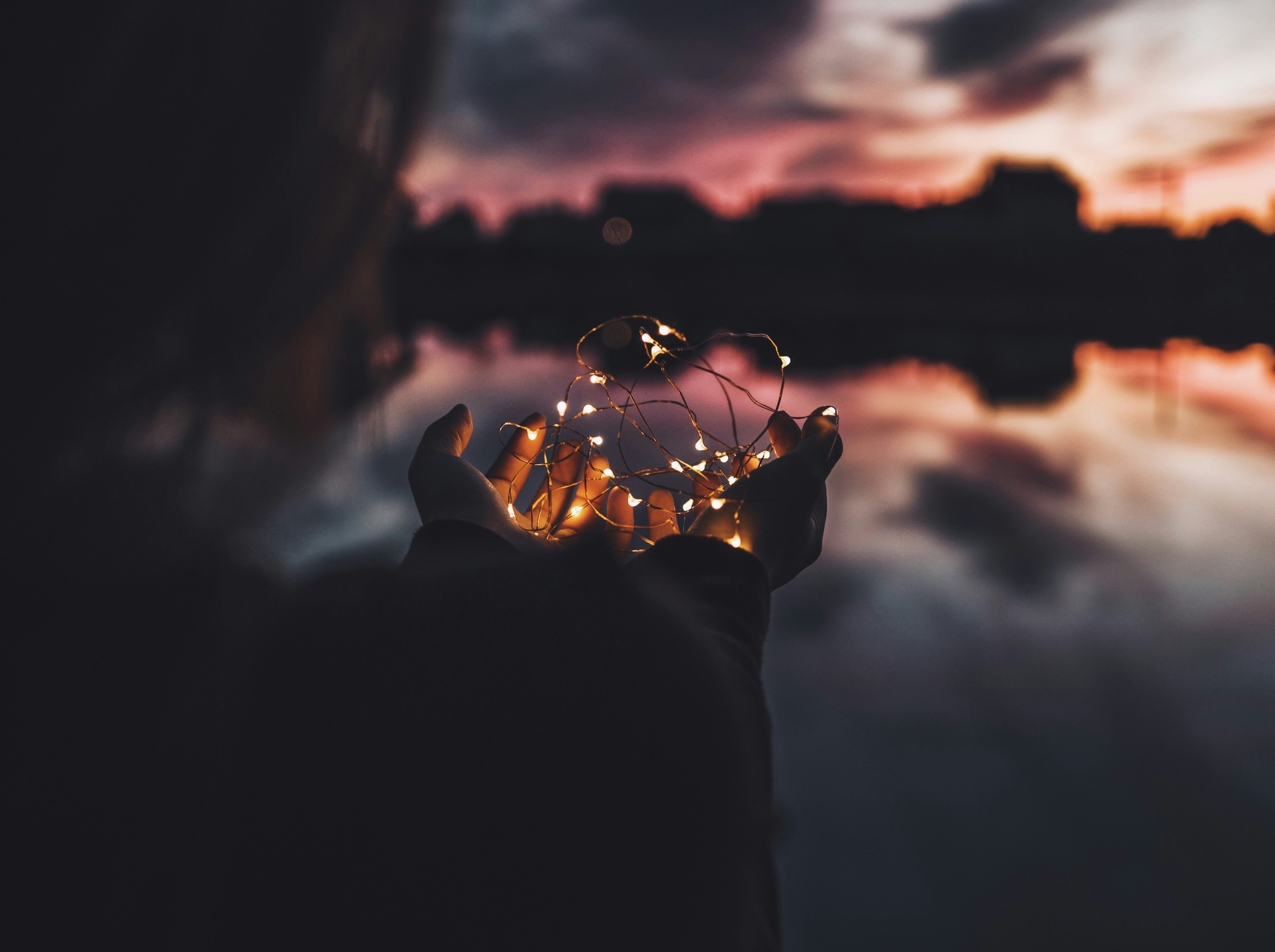 person holding turned on string lights during nighttime